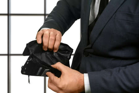 Businessman's hands with empty wallet. Office employee holding empty wallet. Waiting for salary. Truly sad situation.の写真素材