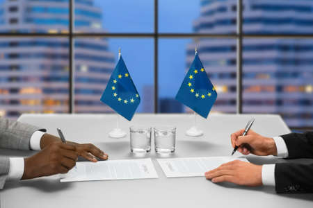 Politicians sign papers near window.の写真素材