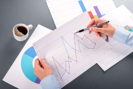 Female hands holding graphic chart. Woman studies graphic chart. The dynamic is changing. Outpacing...