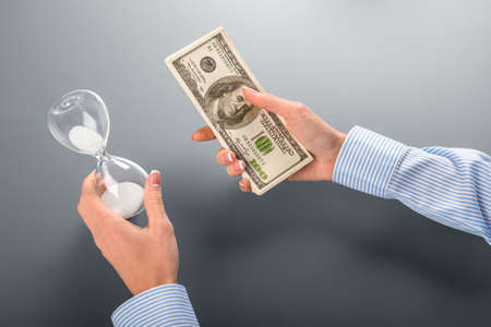 Businesswoman holding money and hourglass.の写真素材
