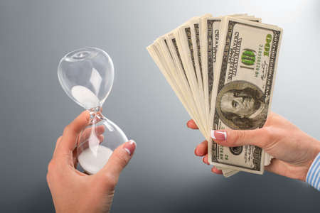 Woman holding cash and hourglass.の写真素材