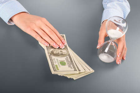 Female touching dollars and hourglass. Woman touches hourglass and cash. Think about your future....