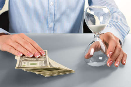 Female touches cash and hourglass.の写真素材