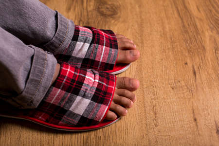Feet in slippers and pants. Gray pants with checkered slippers. Feeling absolutely comfortable. First steps in the morning.の写真素材