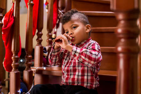 Black boy playing flute. Kid plays flute on stairs. You've got to have skill. Can you impress the audience.の写真素材