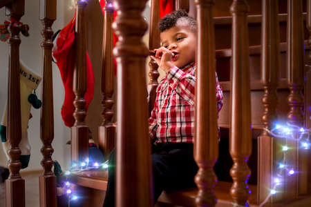 Kid playing flute on stairs. Boy with flute on Christmas. For all the good things. Music always brings joy.の写真素材