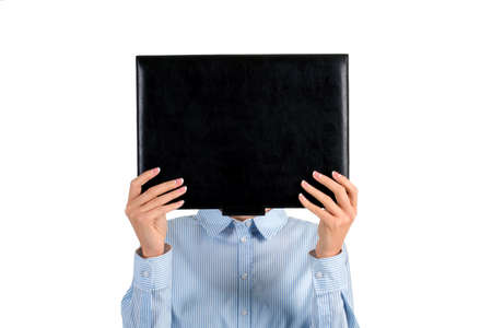 Lady's face covered with folder. Woman holding black leather folder. Mysterious girl covering her face. Intriguing photo of a woman.の写真素材