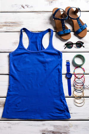 Female tank top and sandals. Woman's clothing on wooden shelf. Simple top and nice accessories. Simple clothing for woman.の写真素材