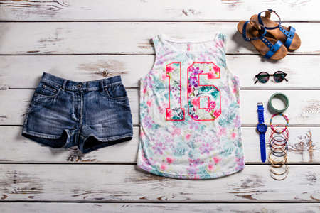 Lady's outfit with jeans shorts. Woodern showcase with female outfit. Casual outfit for teenage girls. Colorful tank top and accessories.の写真素材