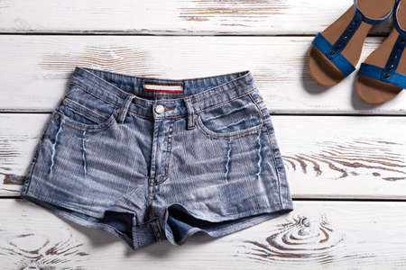 Woman's denim shorts and sandals. Shorts and footwear on shelf. Simple shorts and summer footwear. Summer clothes from new catalog.の写真素材