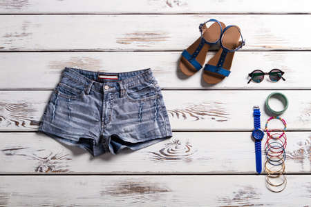 Classic denim shorts and footwear. Showcase with summer clothing. Vintage shorts and nice accessories. Sandals, shorts and small accessories.の写真素材
