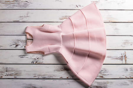 Salmon dress with folds. Cocktail dress on white shelf. Woman's elegant summer garment. Warm-colored piece of clothing.の写真素材