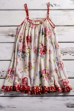 Flax sarafan with thin straps. Vintage sarafan on wooden table. Floral pattern sarafan. Flower pattern garment on showcase.の写真素材