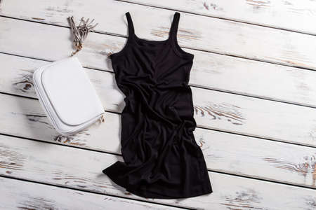 Black u-neck dress and purse. Dark dress on white shelf. Dark dress and white purse. Contrast of clothing and accessory.の写真素材