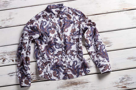 Lady's long sleeve floral shirt. Shirt on white wooden shelf. New garment on old table. Shirt laying on white floor.の写真素材