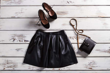 Leather skirt and suede shoes. Skirt and footwear on shelf. Fashionable clothes for modrn girls. Lady's trendy evening clothes.の写真素材