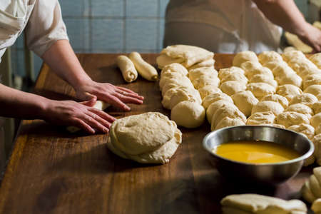 Women bake pies. Confectioners make desserts. Making buns. Dough on the table. Knead the dough.の写真素材