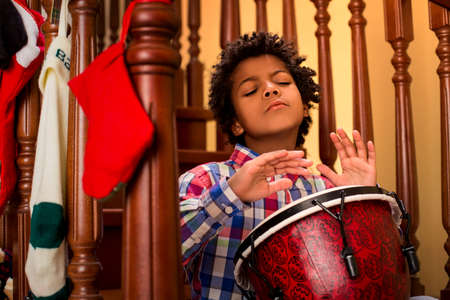Enthusiastic darkskinned boy playing drum. Kid plays drum on stairs. His inspiration is limitless. Let the music flow.の写真素材