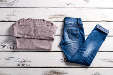 Bateau neckline sweater and jeans. Jeans and sweater on shelf. Blue jeans and beige sweater. Lady's clothes for cool weather.の写真素材