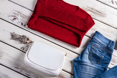 Sweater with handbag and jeans. Womans' clothing laying on shelf. Clothes sale with discounts. Lady's garments in local store.の写真素材