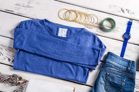 Female sweatshirt with blue jeans. Clothes and accessories on table. Tiny bracelets and spring clothes. Casual garments in clothes shop.の写真素材