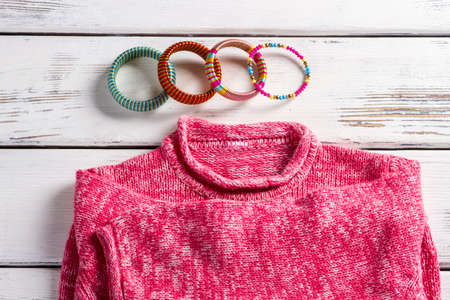 Pink wool pullover and bracelets. Bright pullover on store showcase. Close-up of bracelets and sweater. High-quality clothes in magazine.の写真素材