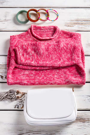 White purse and pink sweater. Sweatshirt and purse on showcase. Bright clothing for young women. Light-colored garment from catalog.の写真素材