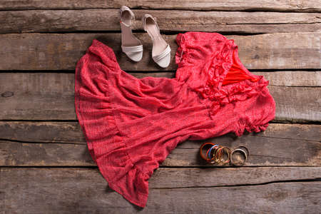 Dress with shoes and bracelets. Lady's outfit on brown table. Aged shelf with stylish outfit. Clothing on aged wooden background.の写真素材