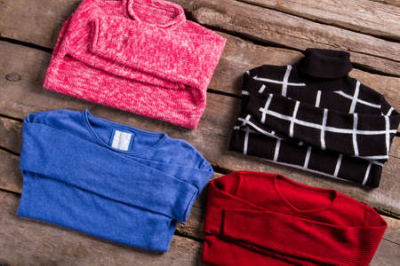 Lady's bright and dark sweaters. New sweaters on old floor. Bright clothing on old table. Sweaters...