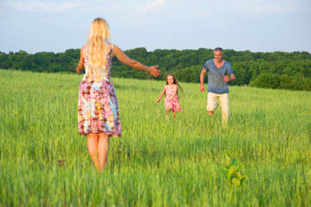 Dad and daughter running to meet  with mom.の写真素材