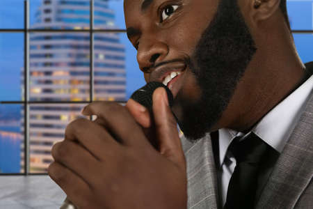 Black singer with microphone. Singer's face on evening background. Combination of talent and skill. What a charming voice.の写真素材