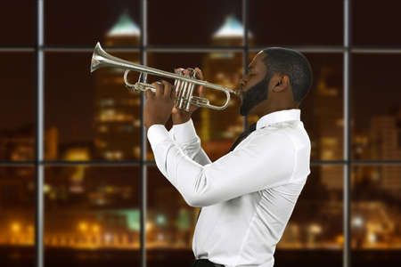 Afro trumpeter playing music. Musician with trumpet at night. Performing hits of past century. Special guest in concert hall.の写真素材
