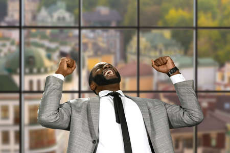 Afro businessman expressing joy. Victorious man on urban background. Sweet moment of joy. Happy and fearless.の写真素材