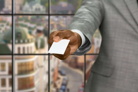 Afroamerican businessman gives visit card. Visit card on urban background. Only authorized access....