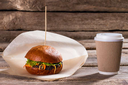 Hamburger and paper coffee cup. Hot drink cup and burger. Small breakfast in cafe. Caffeine will wake you up.の写真素材