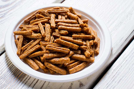 Small crackers on a plate. White plate with brown crackers. Special recipe of homemade crackers. Snack served in local diner.の写真素材