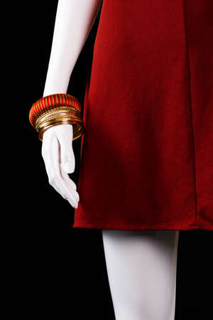 Striped bracelet with red dress. White mannequin wearing gold bracelet. Girl's brand new accessories. Discounts for bijouterie.の写真素材