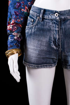 Denim shorts and gold bracelet. Shorts and bracelet on mannequin. Girl's fashionable bracelet on display. Expensive accessory at fair price.の写真素材