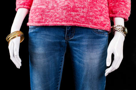 Jeans with bracelet and watch. Accessories and jeans on mannequin. Lady's casual jeans with pullover. Bright apparel on black background.の写真素材