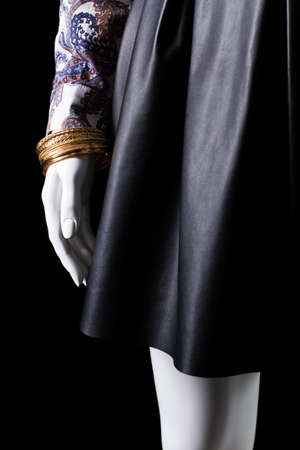 Black skirt and gold bracelet. Mannequin's hand with golden bracelet. New exclusive accessory for women. Stylish and expensive.の写真素材