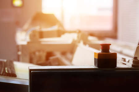 Red button on industrial machine. Conveyor and big red button. Morning in workshop. Press in case of...