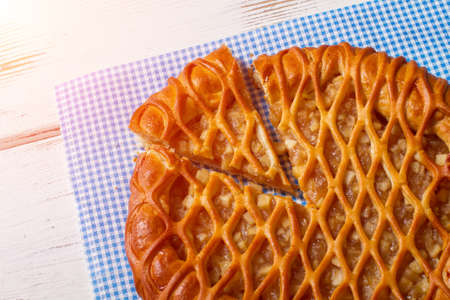 Sliced pie laying on napkin. Pie on white wooden background. Delicious pastry with fruit filling....