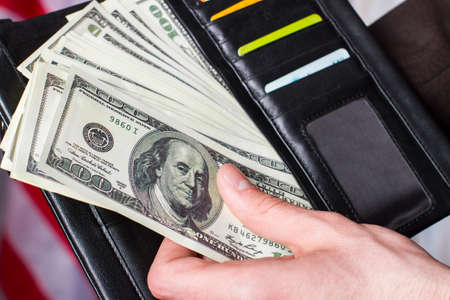 Hand holding dollars and wallet. Wallet with cards and money. It was a busy month. Enough money for...