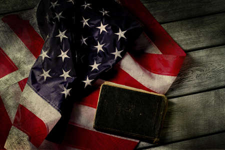 Aged USA flag and book. Book laying beside national flag. Law will protect you. In God we trust.