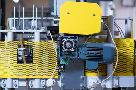 Factory machine with motor. Yellow panels on industrial equipment. Complex device that supplies energy. Wires and bolts.の写真素材