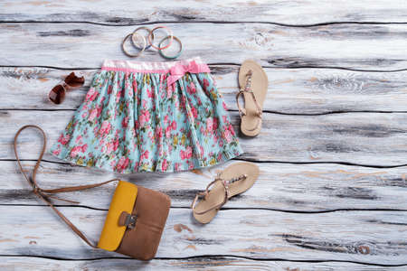 Blue skirt with floral print. Bicolor brown purse and sandals. Woman's accessories on store showcase. Quality material and stylish texture.の写真素材