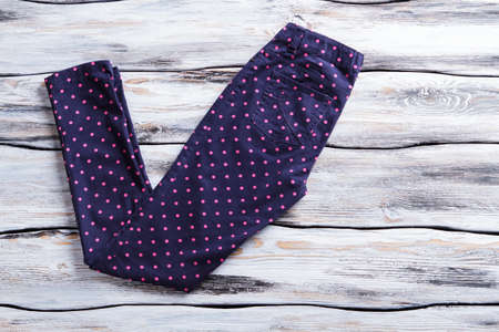 Navy pants with pink dots. Folded trousers on wooden background. Lady's spring pants on shelf. Best merchandise in clothing store.の写真素材
