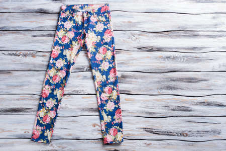 Blue trousers with flower pattern. Female pants on wooden background. Newness and style. Quality clothes sold at discount.の写真素材