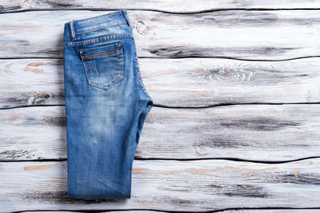 Casual blue jeans. Folded jeans on wooden background. Female trousers of high quality. New item in clothes store.の写真素材