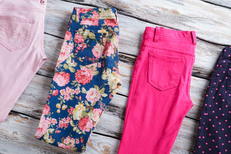 Folded trousers of different color. Trendy pants on wooden background. Selection of merchandise on...